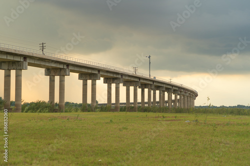 Thai local train on railway bridge at Pa Sak Jolasid Dam, the biggest reservoir in central Thailand, in Lopburi province with cloudy sky in transportation and travel concept. photo