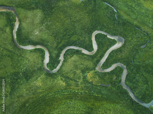 aerial nature landscape of winding river in green field, top view of beautiful texture from drone above