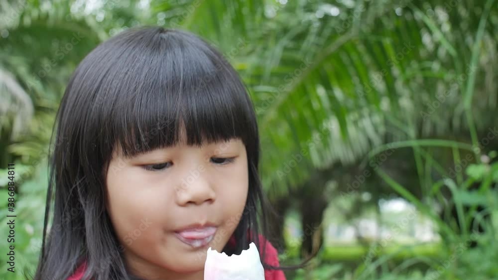Little Asian baby girl enjoys ice cream outdoor. Kid eating ice cream in summer day Little Asian baby girl enjoys ice cream outdoor. Kid eating ice cream in summer day