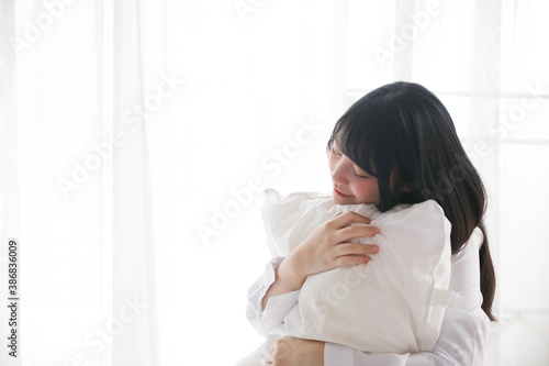Portrait beautiful asian girl sitting with pillow at white bedroom