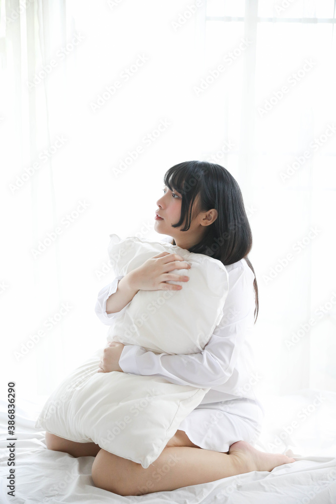 Portrait beautiful asian girl sitting with pillow at white bedroom Portrait beautiful asian girl sitting with pillow at white bedroom