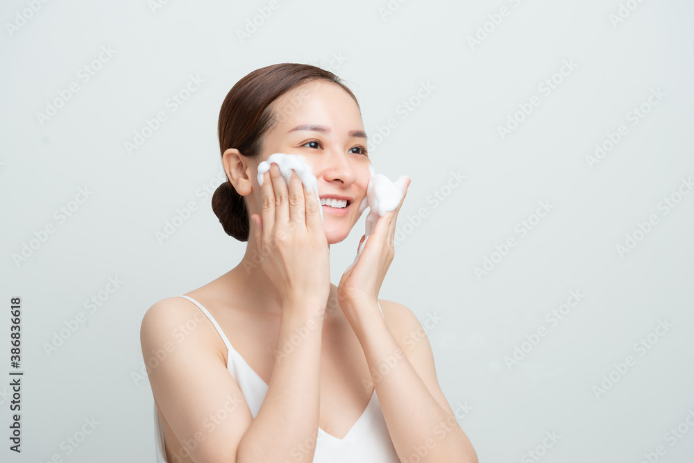 Smiling beautiful asian girl using foaming cleanser. Face washing concept isolated on white background. Smiling beautiful asian girl using foaming cleanser. Face washing concept isolated on white background.