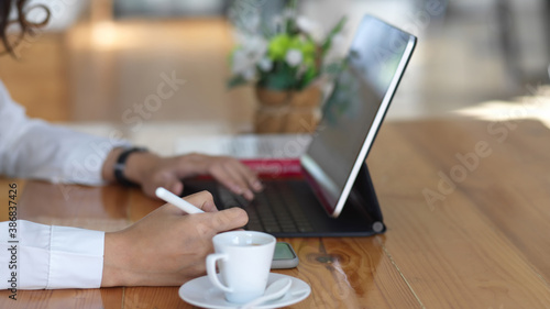 Female hands working with digital tablet and stationery on wooden table