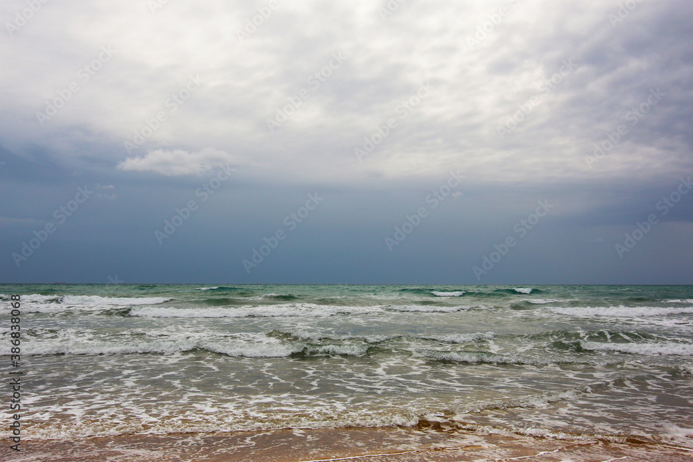In riva al mare; in spiaggia, sul bagnasciuga in una giornata temporalesca d’estate