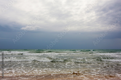 In riva al mare; in spiaggia, sul bagnasciuga in una giornata temporalesca d’estate photo