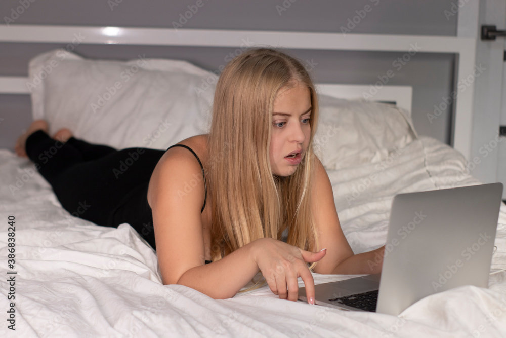 attractive cute shocked surprised blonde with laptop on bed with white sheets. pretty people at isolation. attractive cute shocked surprised blonde with laptop on bed with white sheets. pretty people at isolation.