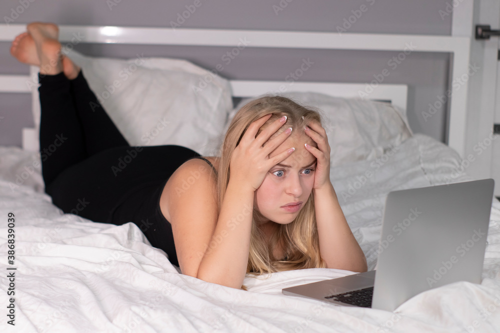 attractive cute shocked surprised blonde with laptop on bed with white sheets. pretty people at isolation. attractive cute shocked surprised blonde with laptop on bed with white sheets. pretty people at isolation.
