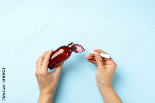 Tableau sur toile Woman pouring syrup in spoon on blue background
