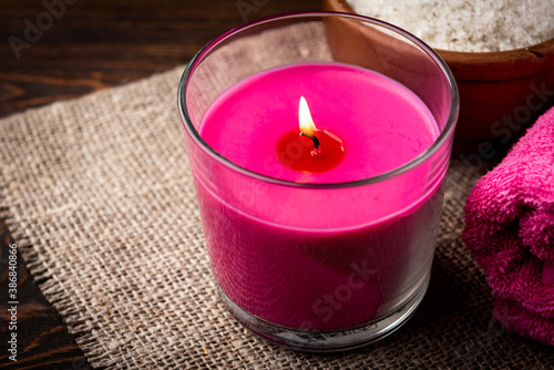 Pink aromatic candle  towel and salt on wooden background.