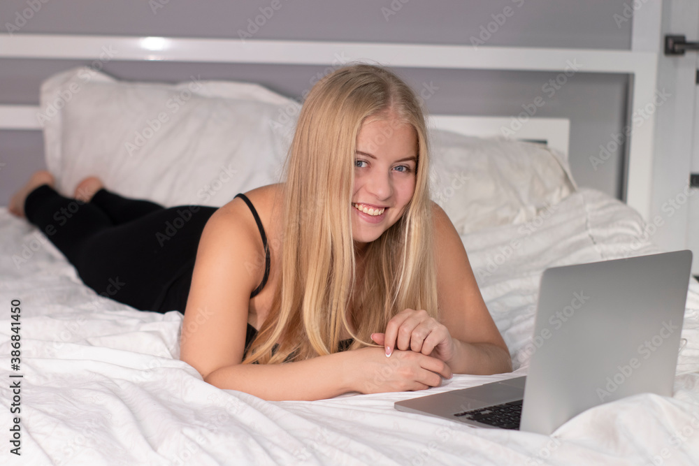 attractive happy cheerful blonde with laptop on bed with white sheet. pretty people at isolation. attractive happy cheerful blonde with laptop on bed with white sheet. pretty people at isolation.