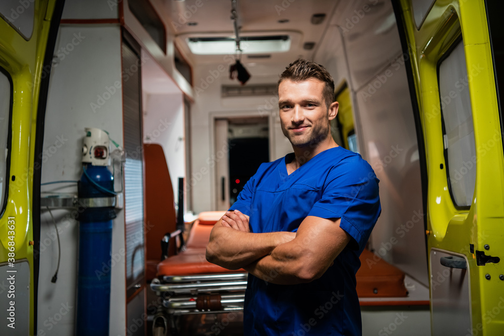 Man in a medical uniform looking at the camera and smiling, ambulance car in the background. Man in a medical uniform looking at the camera and smiling, ambulance car in the background.