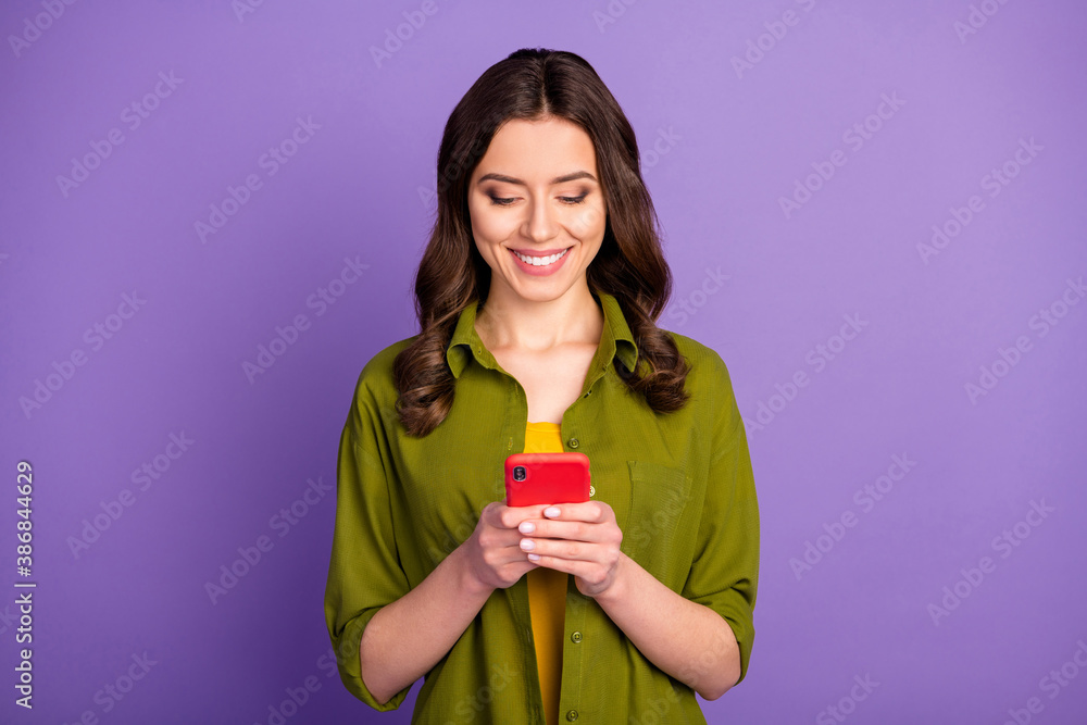 Portrait of positive cheerful girl use cellphone read social network information search comment feedback wear good look outfit isolated over purple color background Portrait of positive cheerful girl use cellphone read social network information search comment feedback wear good look outfit isolated over purple color background