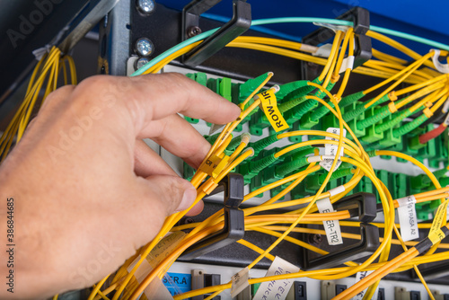 hand of technician plugging in fiber cable into server switch