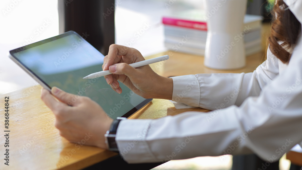 Female hands using mock up digital tablet on wooden bar in cafe Female hands using mock up digital tablet on wooden bar in cafe