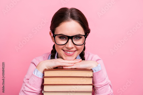 Closeup photo of pretty student lady two braids leaning hands head books pile diligent pupil visit library fond of reading wear shirt pullover specs isolated pastel pink color background