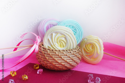 Wicker box with sweets. Colored meringues with a bow.