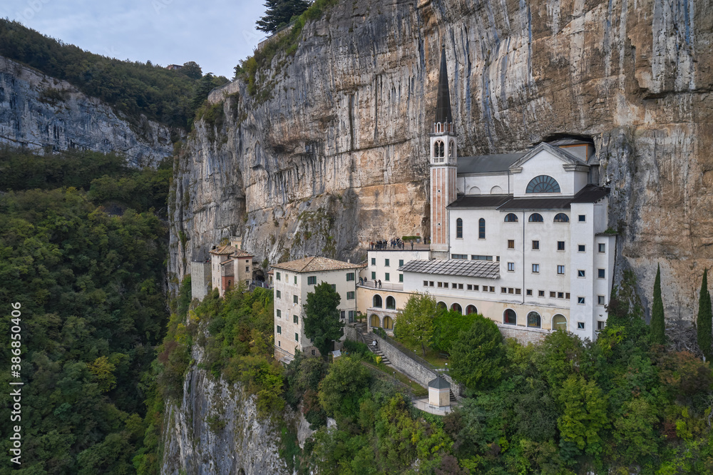 Aerial view of the church on the sheer cliff. Italian church at high altitude in the Alps. The sanctuary is high in the mountains of Italy. The unique Sanctuary Madonna della Corona church in the rock
