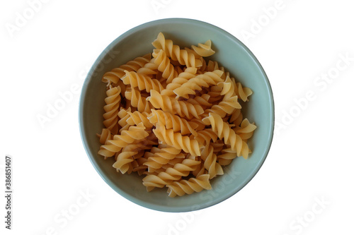 Raw fusilli pasta in a ceramic green plate on a white table. Top view. Isolated.