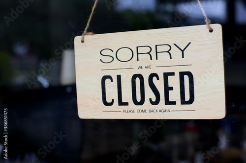 Closed sign door. Text on a wood sign "sorry we are closed please come back again". A closed sign on a wood plate