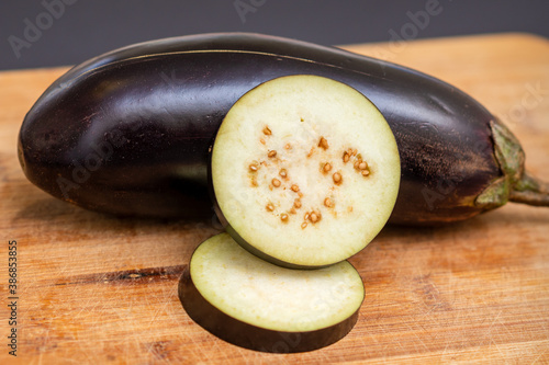 Fresh sliced eggplant on wooden cutting board isolated on black. Cooking ingredients