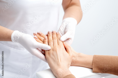 Fotografia Manicurist wearing gloves doing wax massage on female hands with manicure in nai