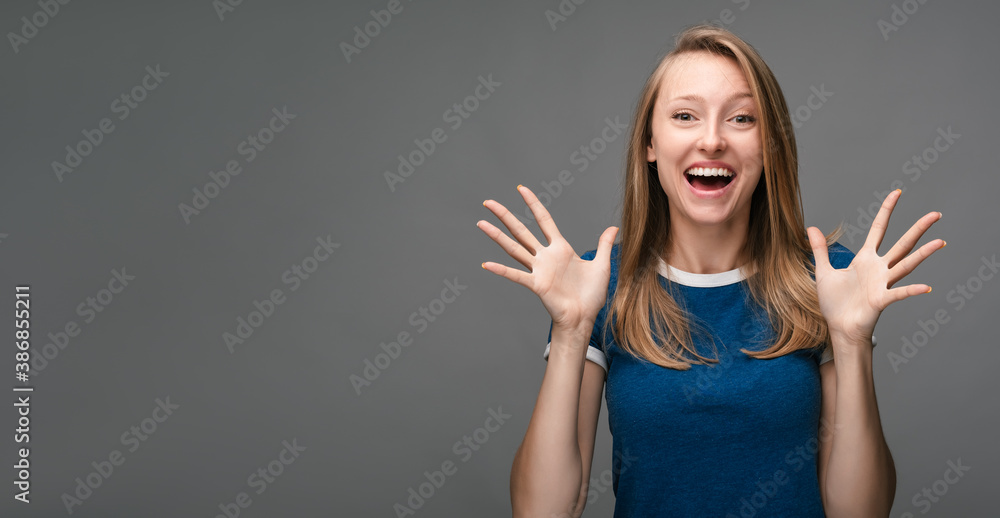 Beautiful surprised blonde woman in blue t shirt on gray background. Surprise, excitement concept. Copy space Beautiful surprised blonde woman in blue t shirt on gray background. Surprise, excitement concept. Copy space