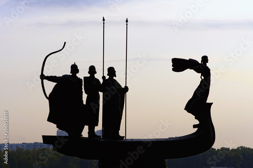 Kyiv, Ukraine-September 26, 2020: Black silhouette of the Monument to the founders of Kyiv on the bank of the Dnieper River. Kyi, Shchek, Horyv and Lybid silhouette against cloudy sky with sun photo