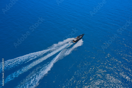 Speed boat movement at high speed aerial view. High-speed yacht of blue color fast motion on blue water in the rays of the sun top view. © Berg