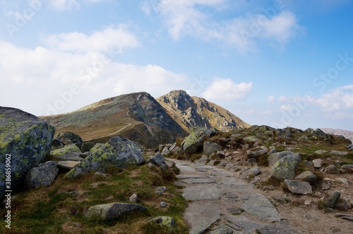 Stone path on a mountain ridge with the tops of rocky mountains in the background 