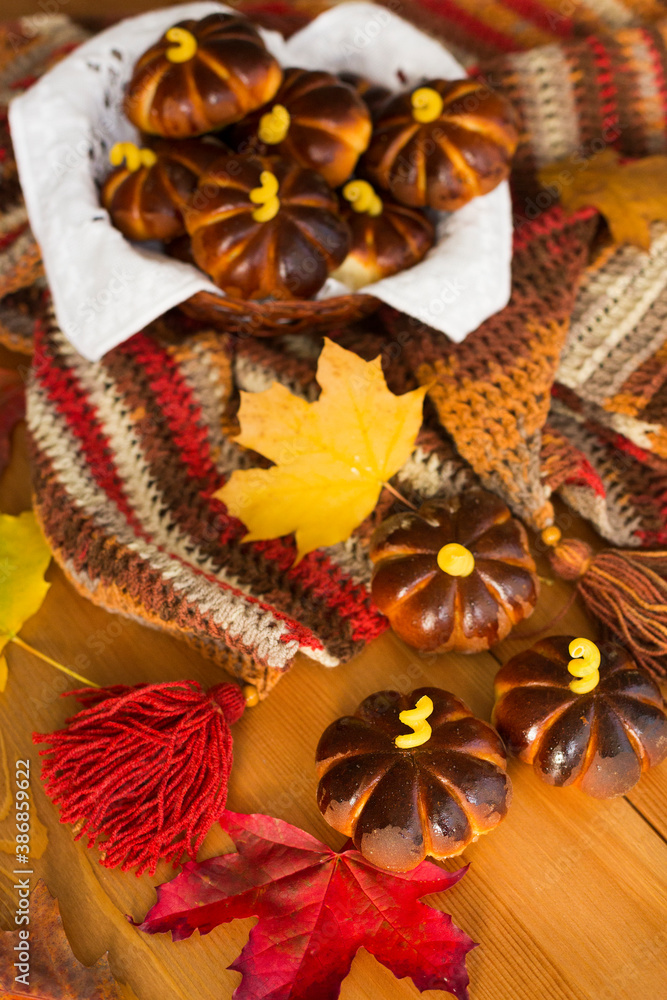 Homemade apple cakes in the shape of pumpkins, cosy colorful shawl or scarf and autumn leaves