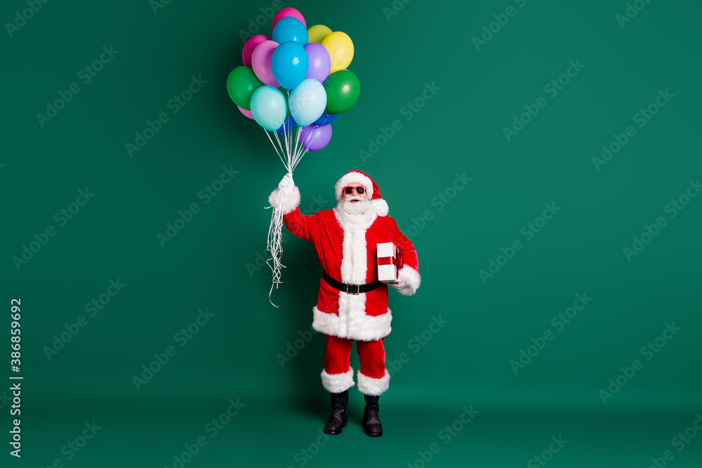 Full length body size view of his he nice handsome cheerful bearded Santa holding in hands bunch helium balls giftbox event festal fast delivery sale isolated over green color background Full length body size view of his he nice handsome cheerful bearded Santa holding in hands bunch helium balls giftbox event festal fast delivery sale isolated over green color background