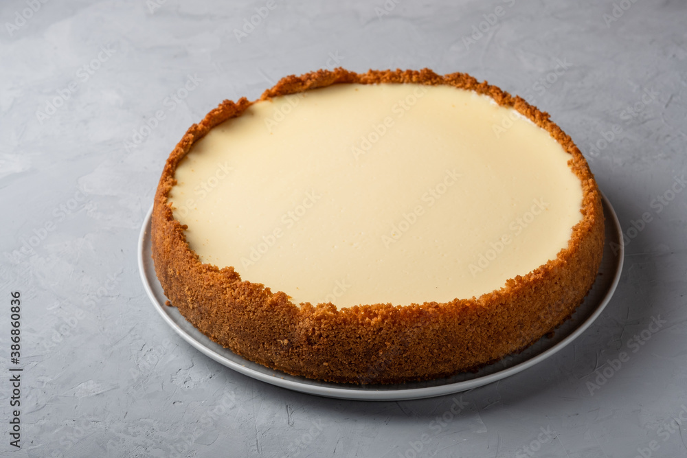 Homemade cooked cheesecake with delicate cream on gray background Homemade cooked cheesecake with delicate cream on gray background