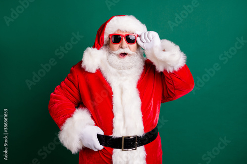 Unbelievable. Photo of retired grandpa white beard open mouth hold eyewear large snowman melt wear red x-mas santa costume coat gloves sunglass headwear isolated green color background