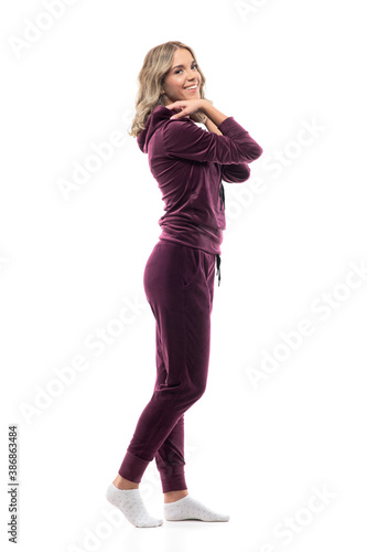 Side view of happy beauty at home getting dressed in burgundy leisurewear in ankle socks. Full body isolated on white background.