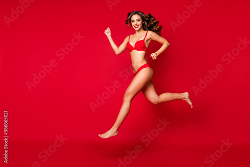 Full length body size view of nice attractive slender slim fit sporty bare foot cheerful wavy-haired girl jumping running goal discount isolated on bright vivid shine vibrant red color background