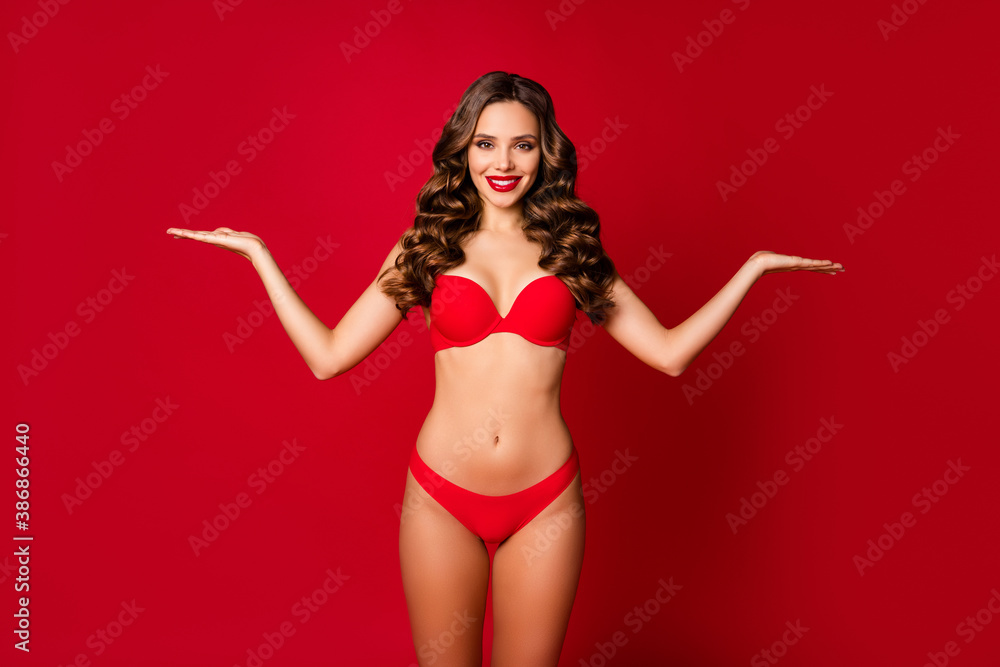 Photo of beautiful lady model advertising underwear hold open palms arms  empty space advising two products sensual slim fit body figure wear  brassiere panties isolated red color background Stock Photo