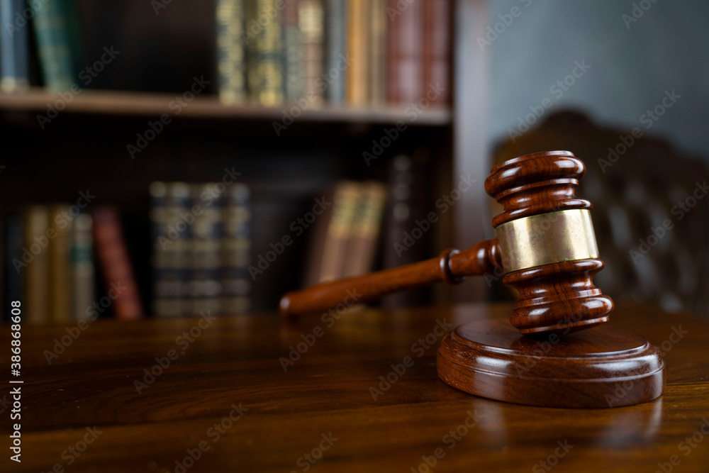 Law theme. Judge chamber. Gavel on brown desk. Collection of legal books in the bookshelf. Law theme. Judge chamber. Gavel on brown desk. Collection of legal books in the bookshelf.