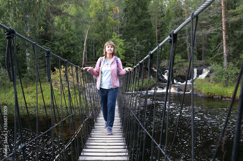 Woman on wooden suspension bridge over Ruskeala waterfall