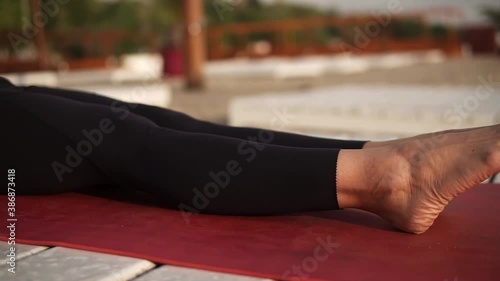 Athletic woman practicing yoga on mat on the beach performing yoga elements, upwards plank photo