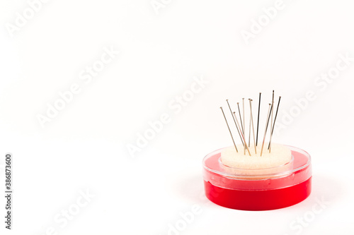 Red pack of tailor pins. Needle storage box with foam rubber pincushion. Sewing tool banner isolated on white background with copy space