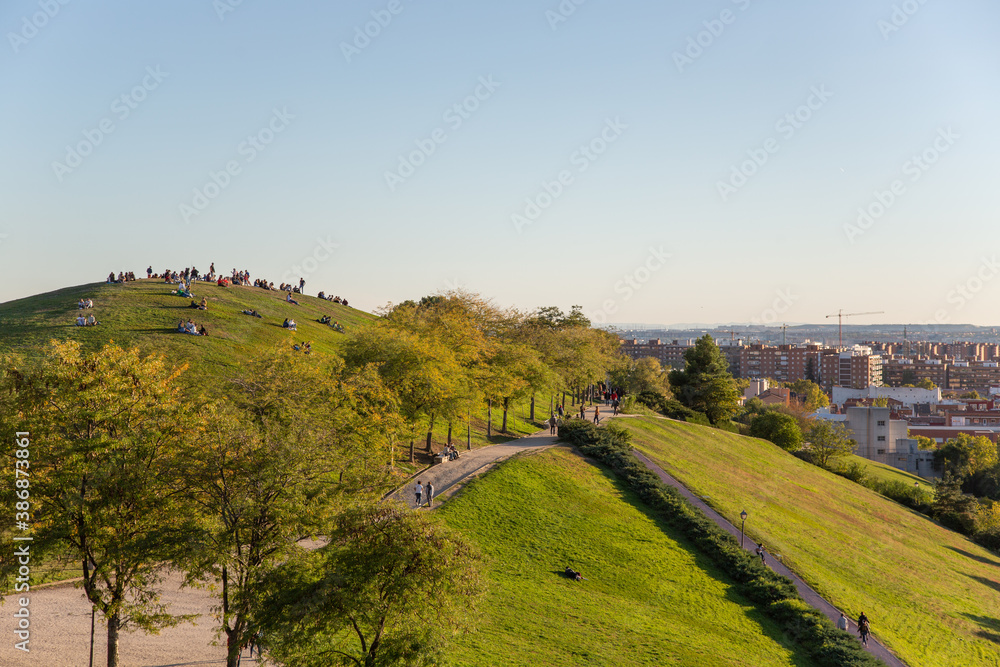 View of the green hills of the city park. People are resting in the autumn park. The park Cerro del Tio Pio. Madrid, Spain. 