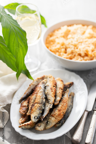 fried small sardines with tomato rice on white dish on ceramic