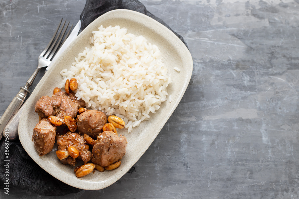 meat with nuts and boiled rice on white plate on ceramic background meat with nuts and boiled rice on white plate on ceramic background