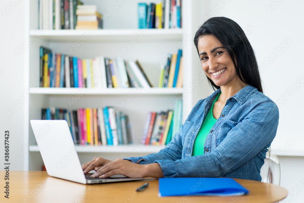Laughing mexican mature adult woman working online at computer Laughing mexican mature adult woman working online at computer