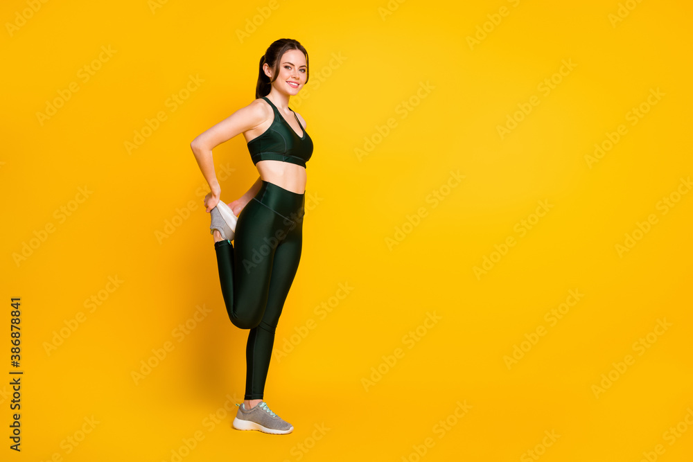 Full length body size profile side view of her she nice cheerful girl doing physical exercise stretch isolated on vibrant yellow color background Full length body size profile side view of her she nice cheerful girl doing physical exercise stretch isolated on vibrant yellow color background