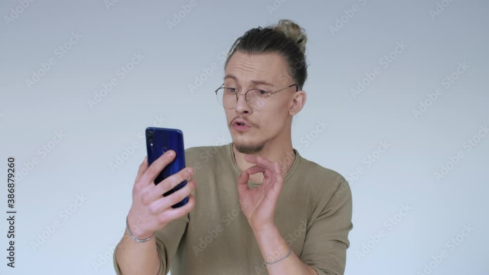A handsome blogger sings on a smartphone during an online broadcast. A handsome blogger sings on a smartphone during an online broadcast.