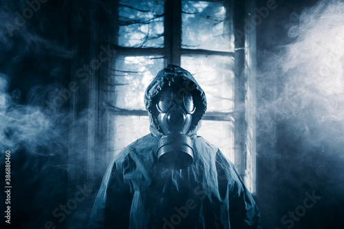 Billede på lærred Spooky person with gas mask holding a lamp in dense fog in an abandoned building with eerie feeling