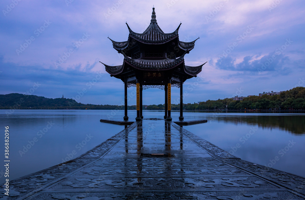 Historic Jixian Pavilion of traditional Chinese architecture style on West Lake at dawn, Hangzhou, Zhejiang, China. Tourist attraction. Beauty of symmetry.