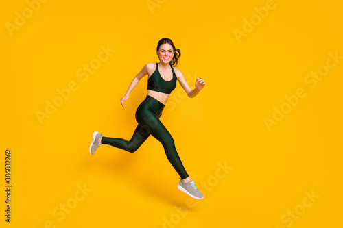 Full length profile photo of lady jump high up training marathon finish line wear sports suit shoes isolated yellow color background © deagreez