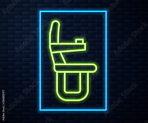 Glowing neon line Airplane seat icon isolated on brick wall background. Vector.